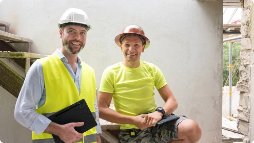 Zwei Bauleiter mit Schutzhelmen auf einer Baustelle