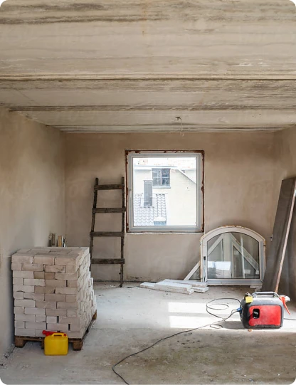 Unfertiger Rohbauraum mit Baumaterial und Fenster ohne Aufsicht