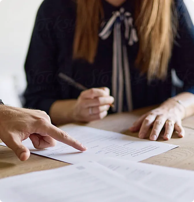 Beraterin und Kunde gehen am Tisch gemeinsam Förderunterlagen durch