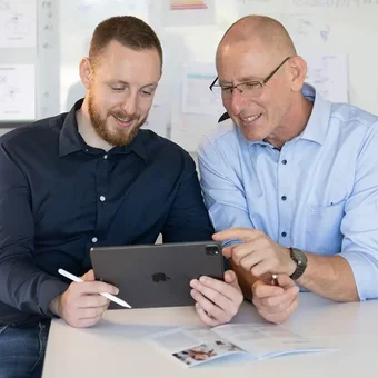 Zwei Berater besprechen Unterlagen auf einem Tablet