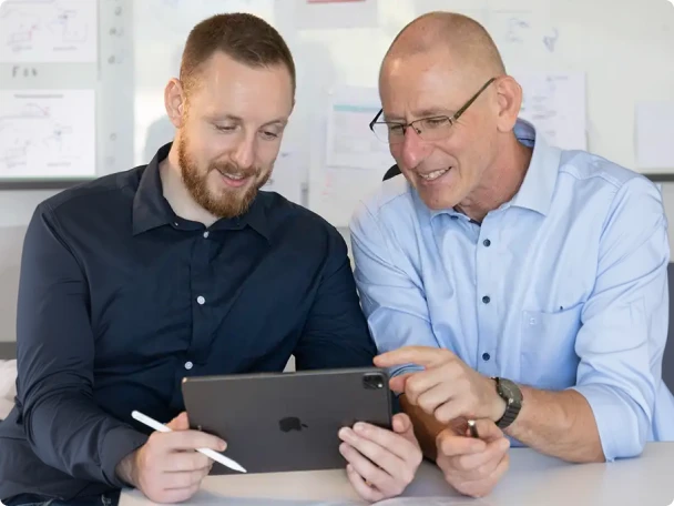Zwei Männer besprechen technische Zeichnungen auf einem Tablet