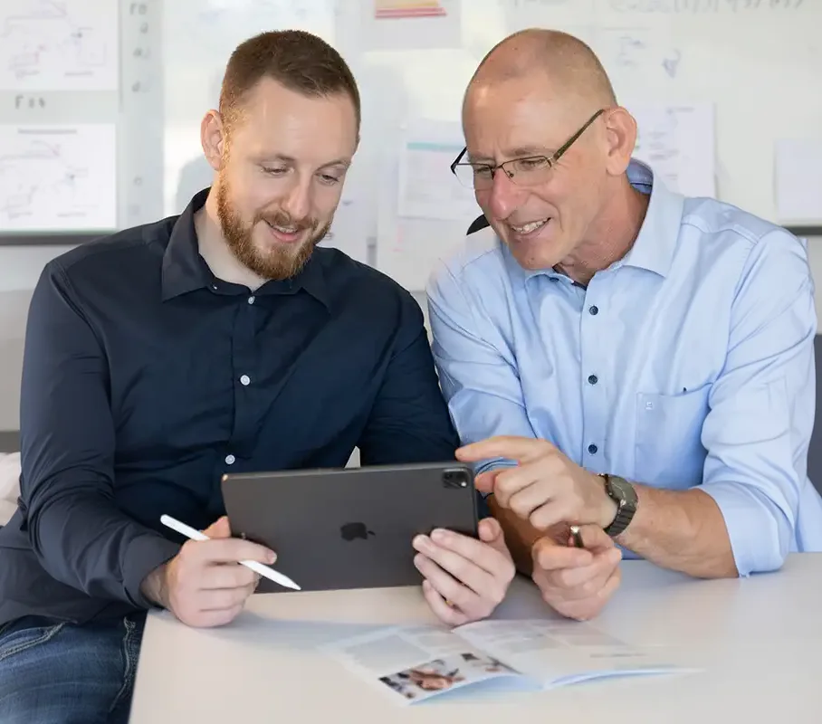 Zwei Männer besprechen Unterlagen auf einem Tablet